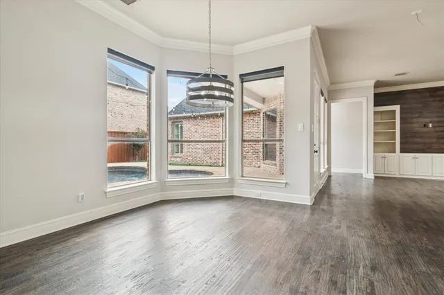 an empty room with wooden floor a ceiling fan and windows
