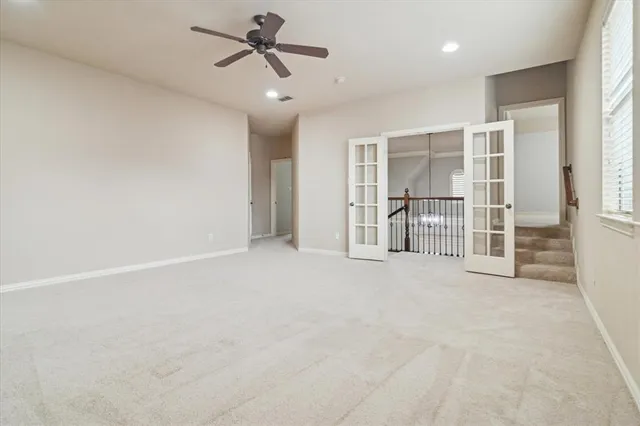 an empty room with chandelier fan and windows