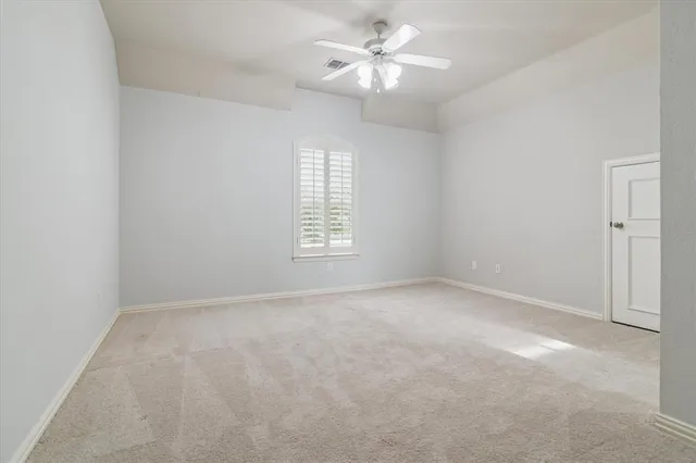 an empty room with a window and a ceiling fan