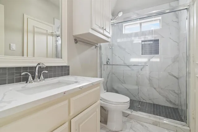 a bathroom with a granite countertop sink toilet a mirror a vanity and shower