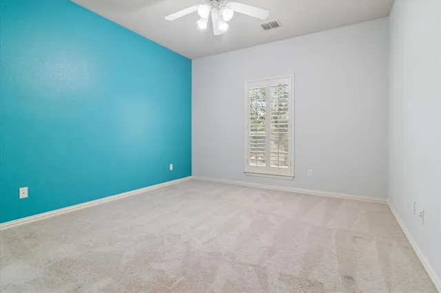 an empty room with a chandelier fan and windows