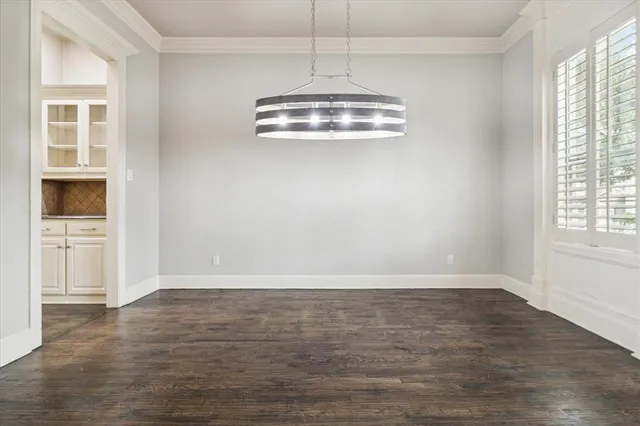 an empty room with wooden floor cabinet and windows