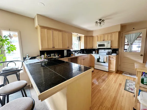 a kitchen with stainless steel appliances granite countertop a stove top oven a sink dishwasher and cabinets with wooden floor