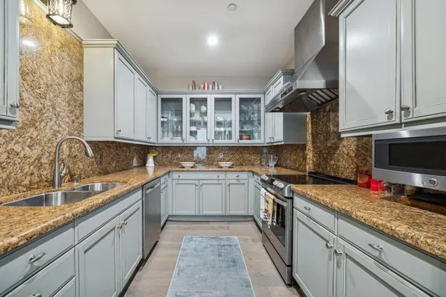 a kitchen with stainless steel appliances granite countertop a sink and dishwasher a stove top oven with wooden floor