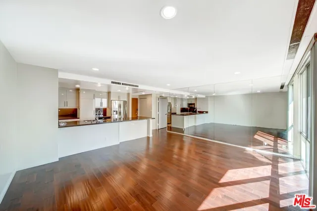 a view of a living room a kitchen with wooden floor and a large window