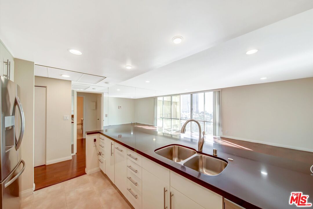 2160 Century Park, Unit 1503 Los Angeles, CA 90067 - Photo 9 of 22 a kitchen with granite countertop a sink and a refrigerator