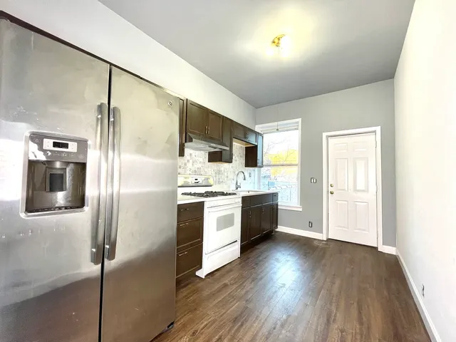 a large kitchen with a refrigerator and white cabinets