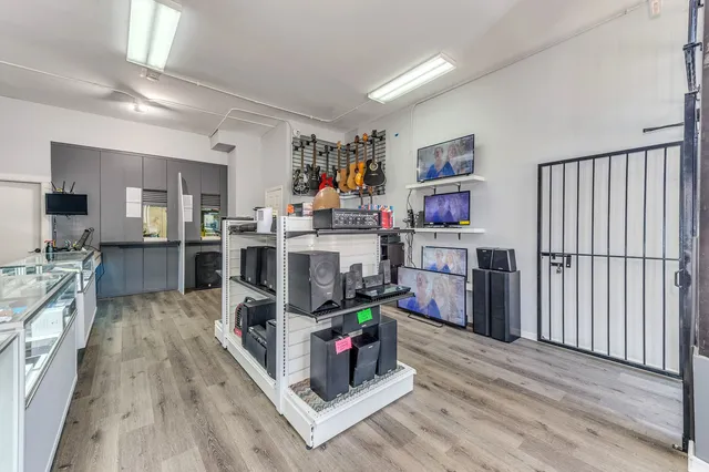 a living room with stainless steel appliances furniture a flat screen tv and a refrigerator