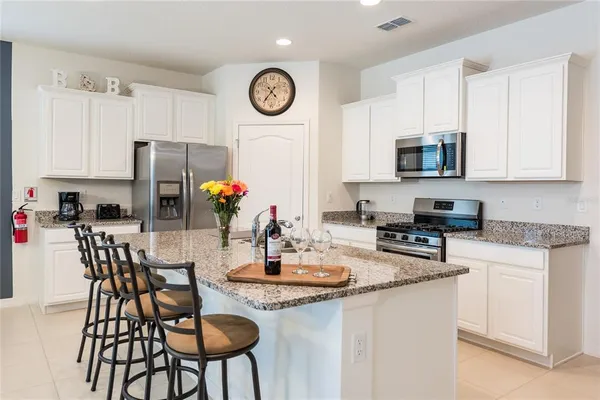 a kitchen with stainless steel appliances granite countertop a table and chairs in it