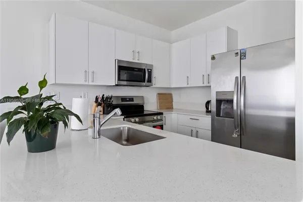 a kitchen with a refrigerator sink and white cabinets