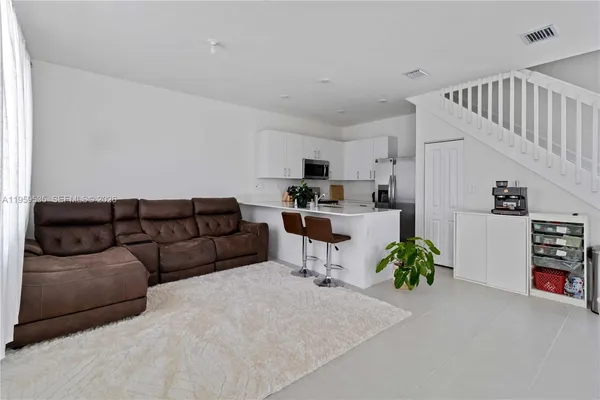 a living room with furniture and a dining table with kitchen view