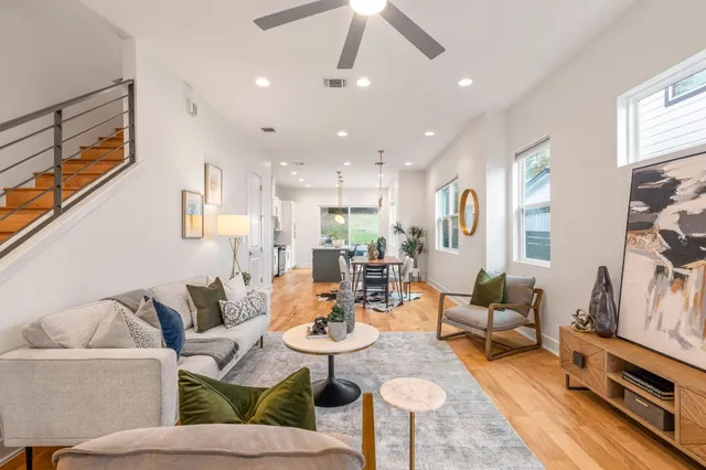 a living room with furniture kitchen view and a wooden floor