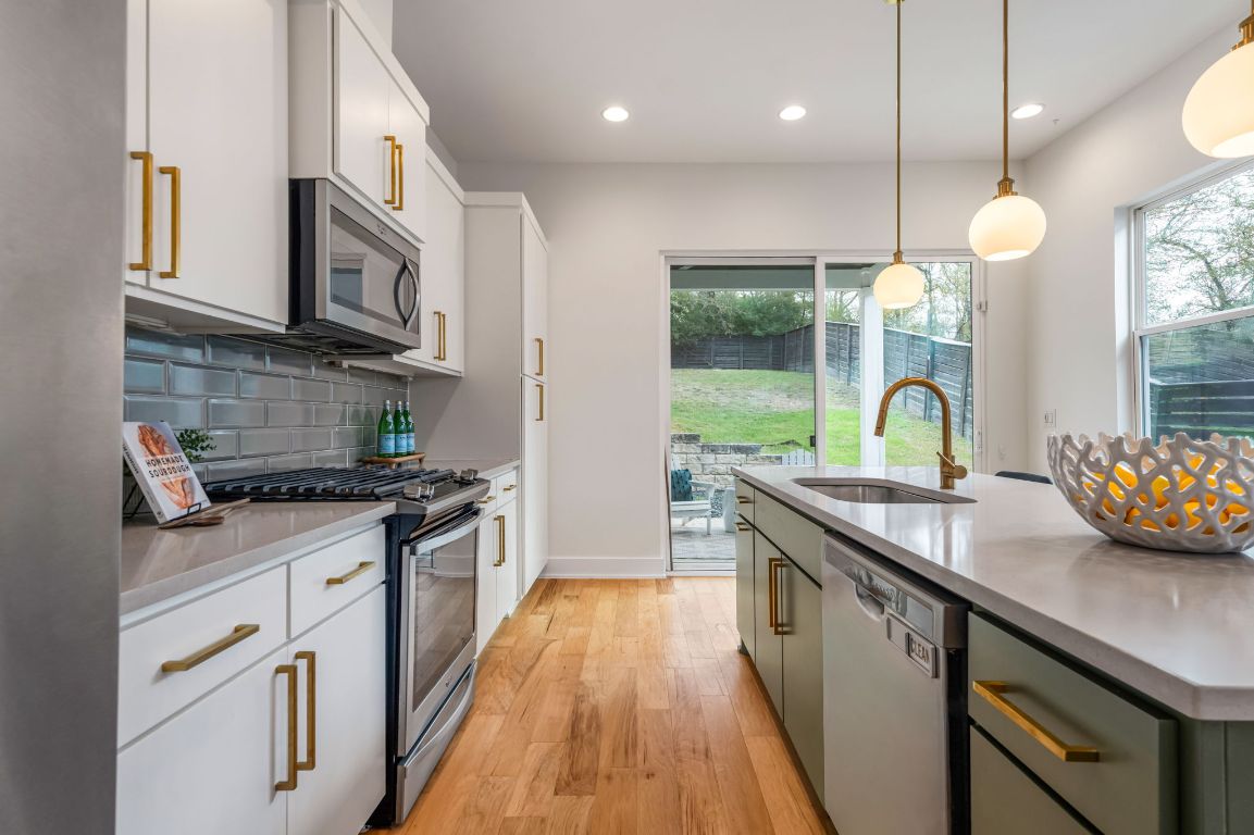 1301 Cometa Street, Unit A Austin, TX 78721 - Photo 9 of 38 Bright kitchen layout with gas cooking, a sleek subway tile backsplash, and a view toward the sliding doors that open to the backyard patio