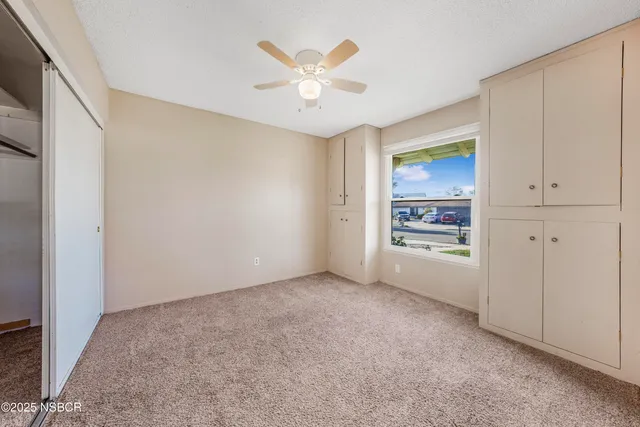 an empty room with cabinet and ceiling fan