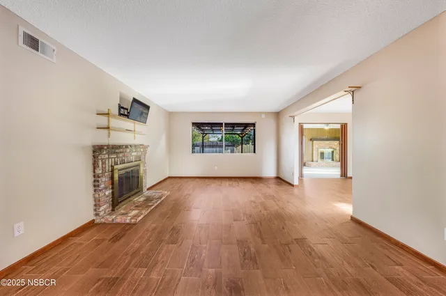 an empty room with wooden floor fireplace and windows