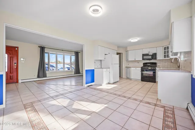 a large white kitchen with cabinets and a refrigerator