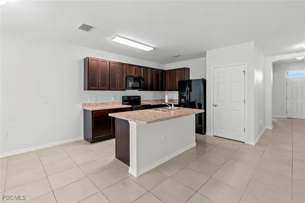 a kitchen with kitchen island granite countertop a stove top oven a sink a counter top space and cabinets
