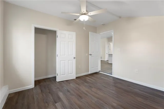 an empty room with wooden floor and a ceiling fan