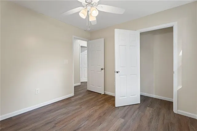 an empty room with wooden floor and ceiling fan