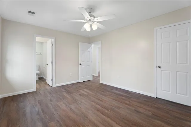 an empty room with wooden floor and a ceiling fan
