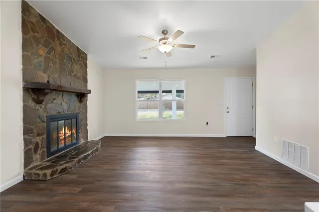 a view of an empty room with wooden floor fireplace and a window