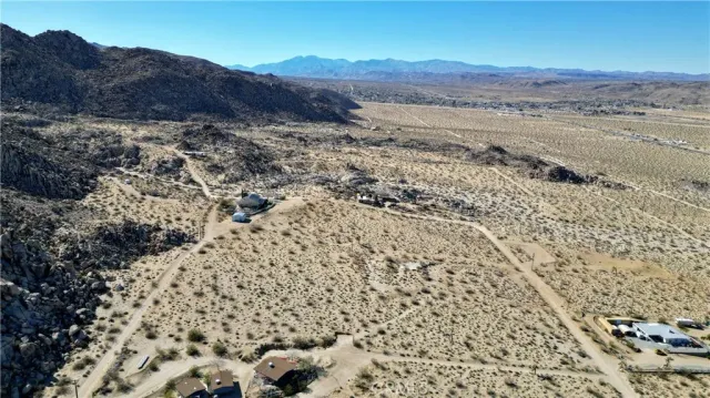 a view of a dry field with mountains in the background