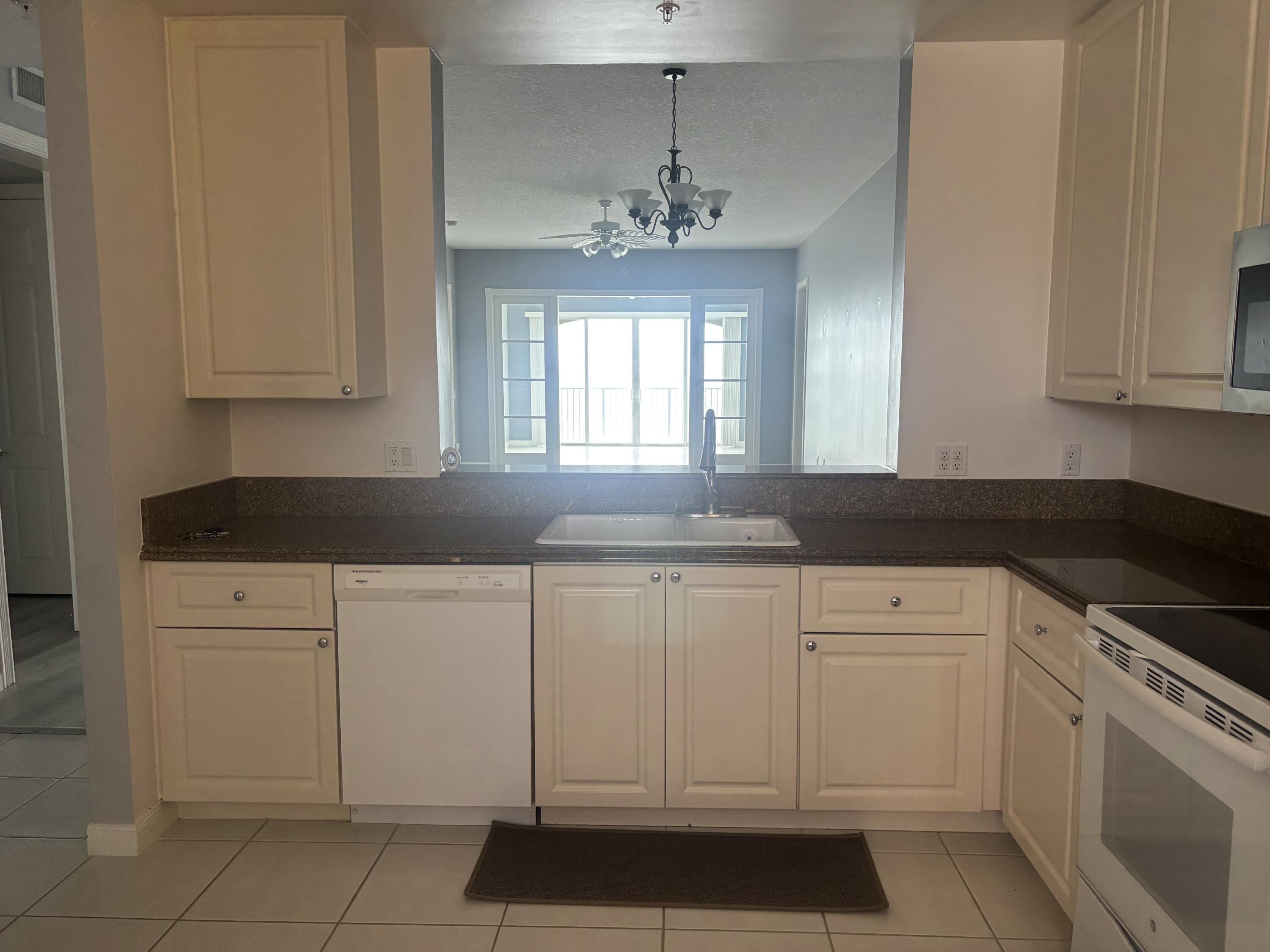 31 Harbour Isle Drive West, Unit 303 Fort Pierce, FL 34949 - Photo 4 of 31 a kitchen with white cabinets granite counter tops and a stove