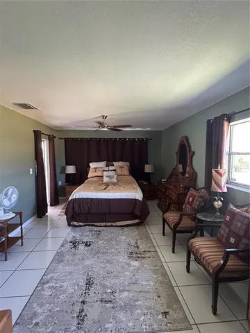 a spacious bedroom with a bed a couch and a dresser with wooden floor