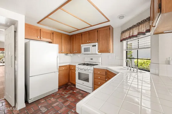 a kitchen with granite countertop a refrigerator a stove top oven and sink