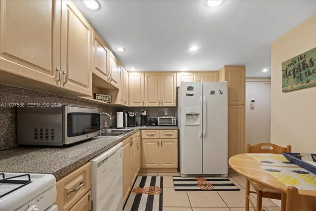 a kitchen with stainless steel appliances a refrigerator a stove a sink and white cabinets