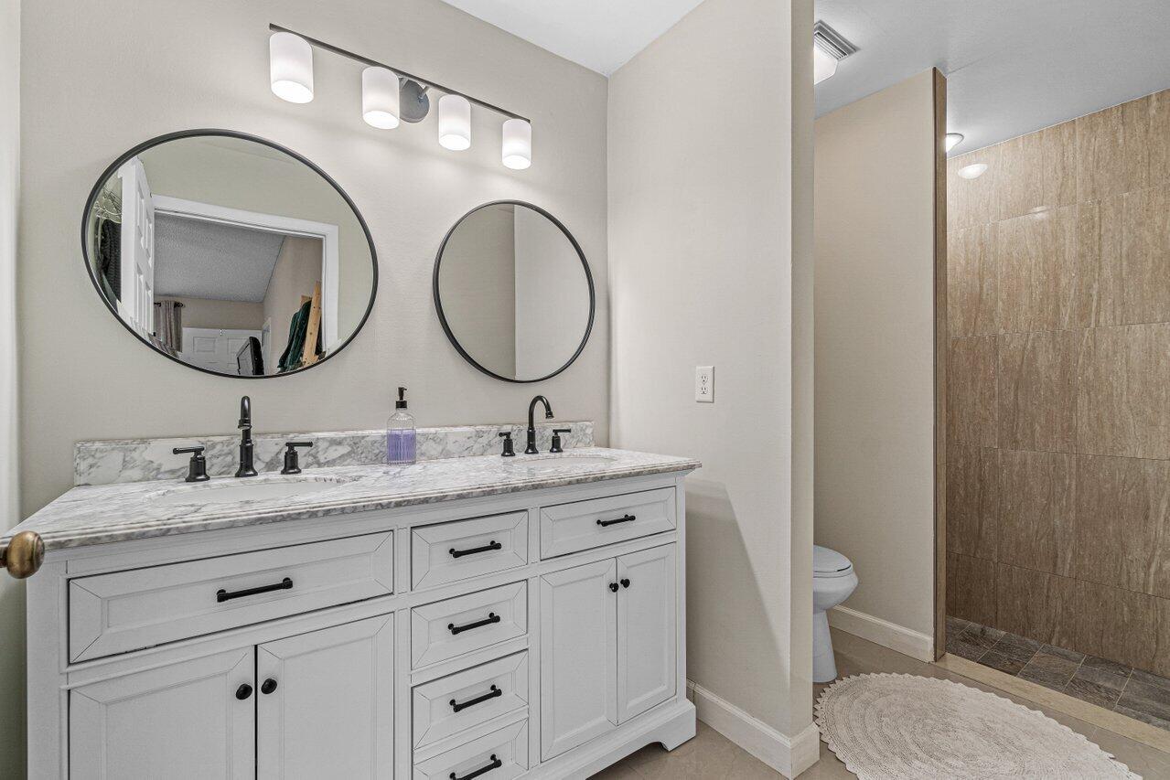 241 Meadows Drive Boynton Beach, FL 33436 - Photo 15 of 24 a bathroom with a granite countertop toilet a sink and a mirror