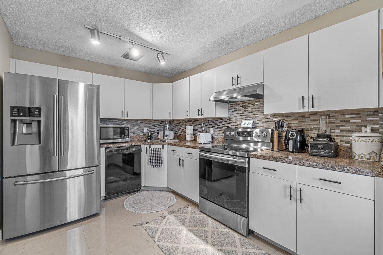 241 Meadows Drive Boynton Beach, FL 33436 - Photo 10 of 24 a kitchen with cabinets stainless steel appliances and sink