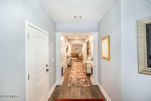 a view of a hallway with wooden floor and a living room