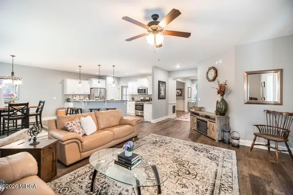 a living room with furniture kitchen view and a wooden floor