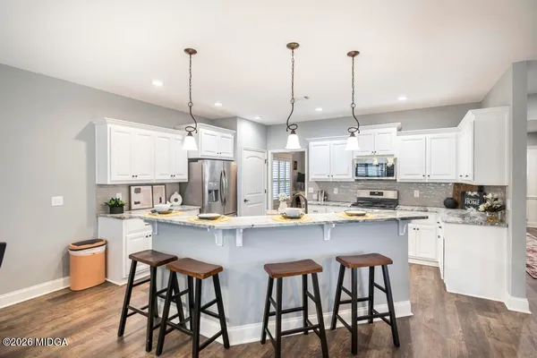a kitchen with stainless steel appliances granite countertop a sink a stove a refrigerator and chairs