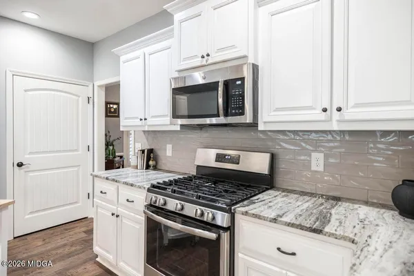 a kitchen with granite countertop white cabinets and stainless steel appliances