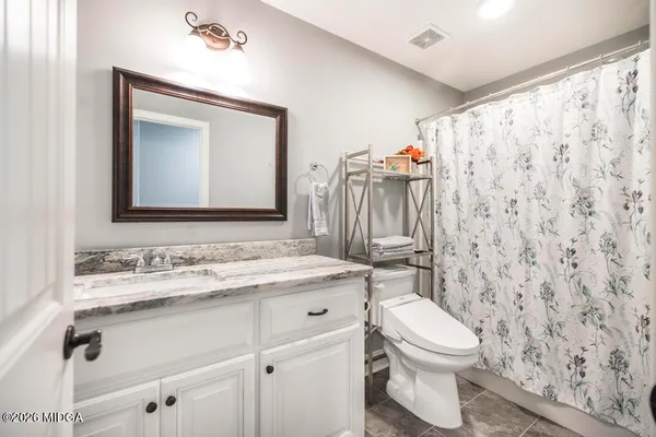 a bathroom with a toilet sink vanity and mirror