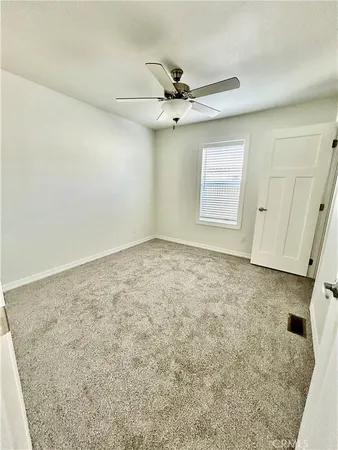 an empty room with a ceiling fan and carpet