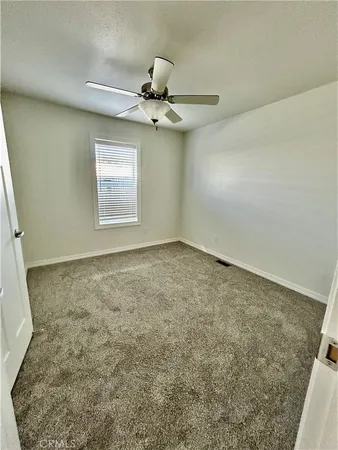an empty room with windows and fan