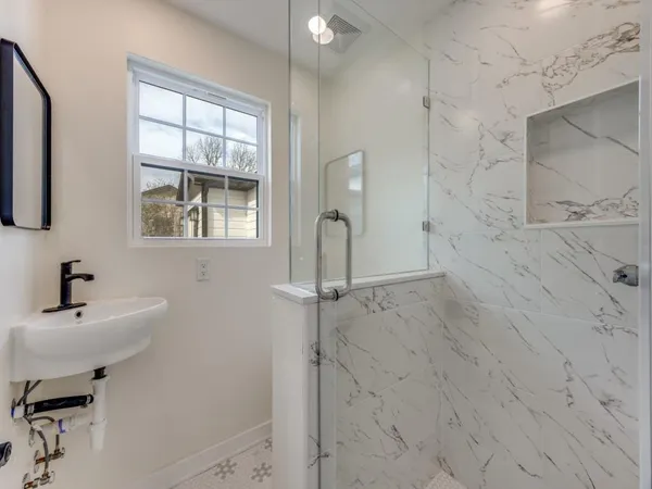 a bathroom with a sink a window and shower
