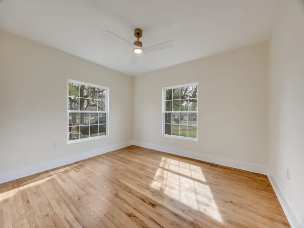 a view of an empty room with a window and wooden floor