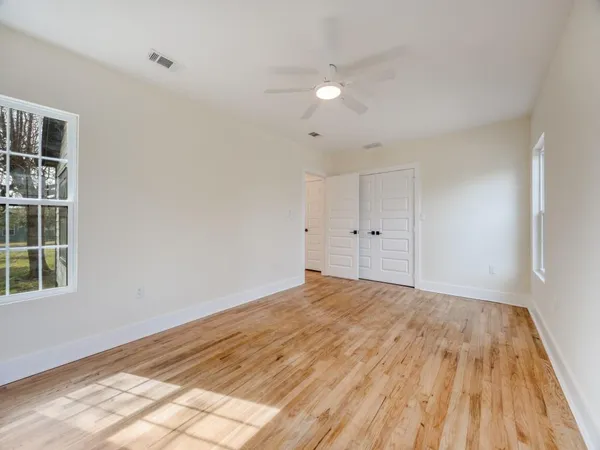 a view of empty room with wooden floor and fan