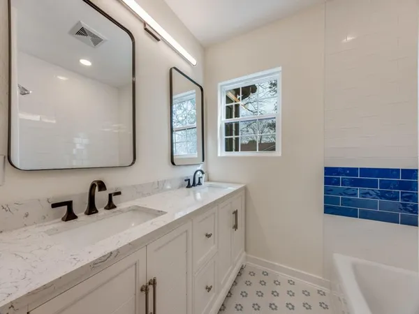 a bathroom with a double vanity sink a mirror and a bathtub