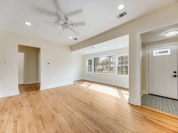 a view of an empty room with a window and wooden floor