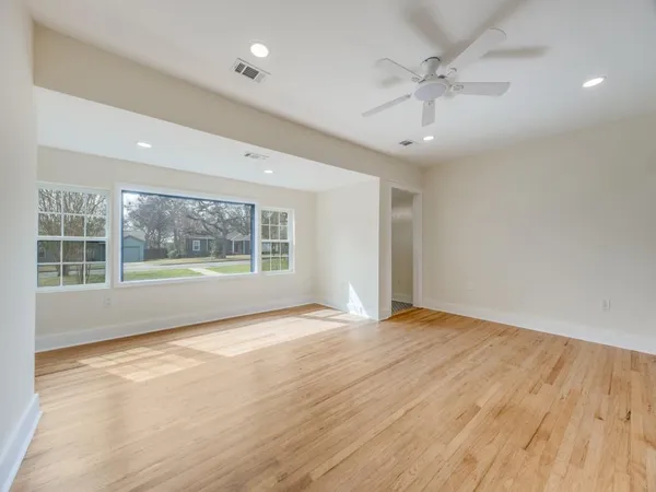 a view of an empty room with a window and wooden floor