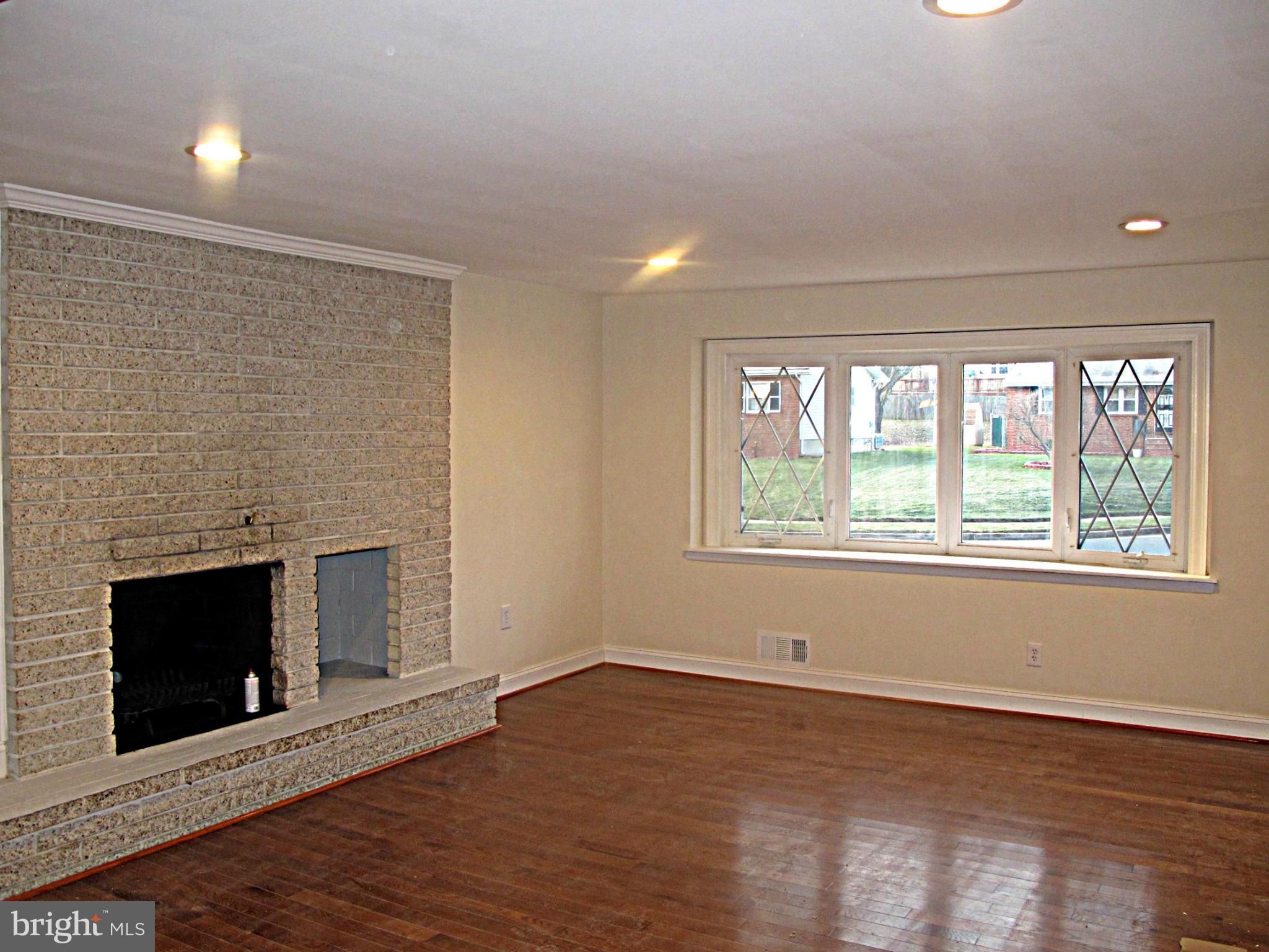 8910 Maplebrook Road Randallstown, MD 21133 - Photo 3 of 18 an empty room with wooden floor fireplace and windows