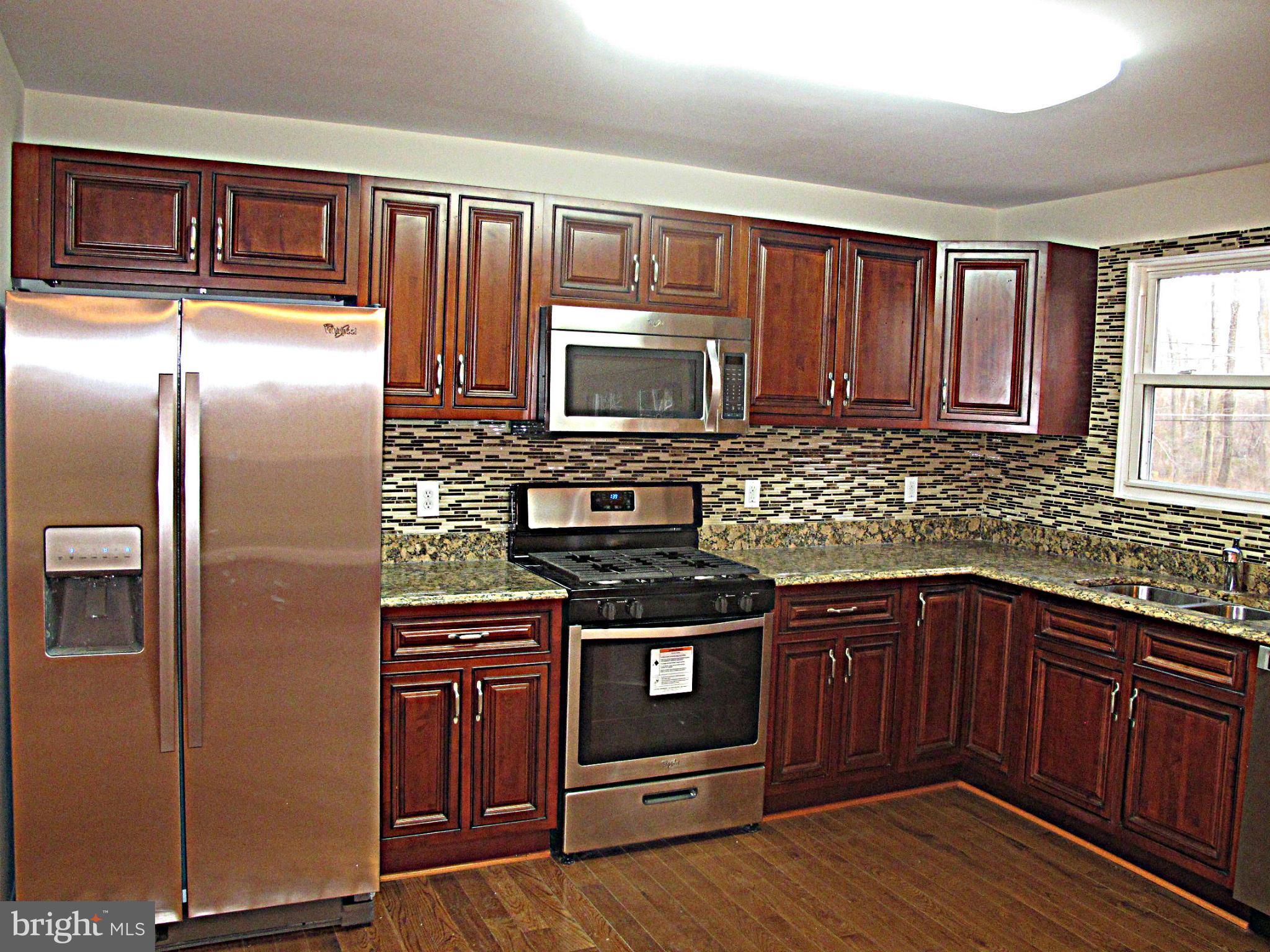8910 Maplebrook Road Randallstown, MD 21133 - Photo 5 of 18 a kitchen with granite countertop wooden cabinets stainless steel appliances and a window