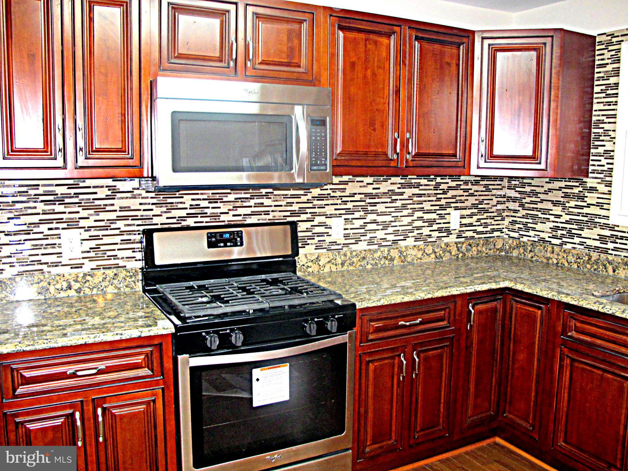 8910 Maplebrook Road Randallstown, MD 21133 - Photo 6 of 18 a kitchen with granite countertop wood cabinets stainless steel appliances and a sink