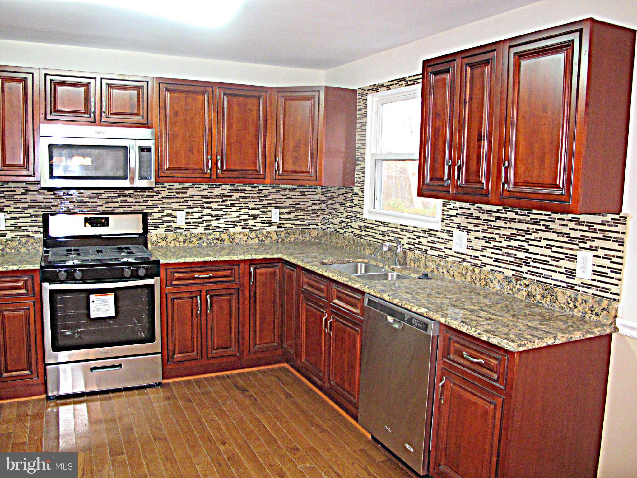 8910 Maplebrook Road Randallstown, MD 21133 - Photo 7 of 18 a kitchen with stainless steel appliances granite countertop wooden cabinets a stove top oven