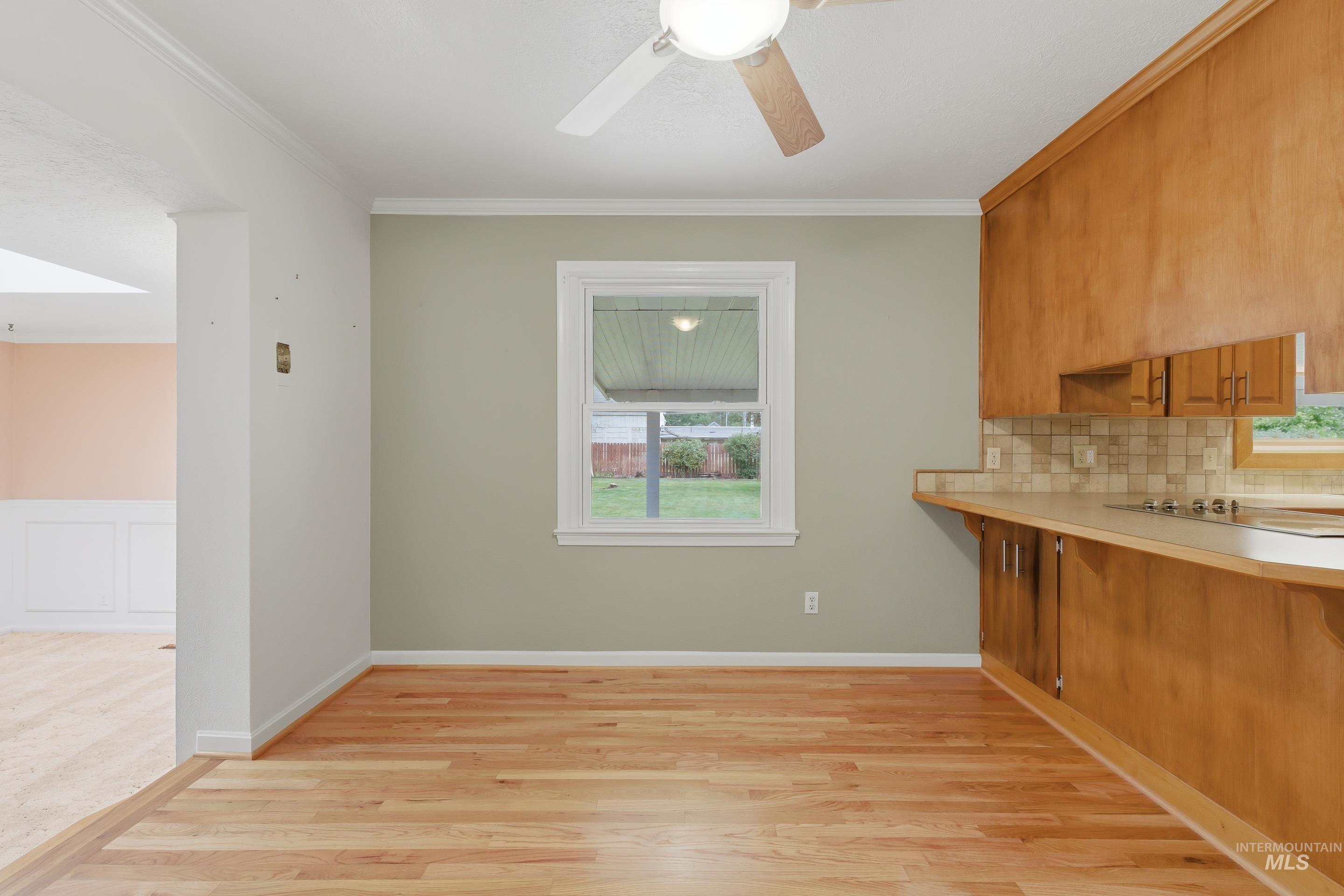 504 West Howe Street Boise, ID 83706 - Photo 16 of 47 Open concept space featuring wood-finish flooring, a ceiling fan, and a kitchen area with wood cabinetry, a tiled backsplash, and light countertops